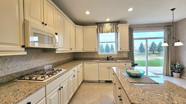 kitchen with hanging light fixtures, white appliances, a wealth of natural light, and sink