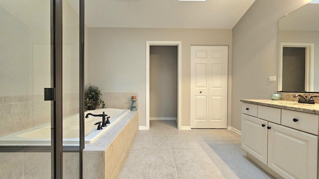 bathroom featuring tile patterned floors, vanity, and a relaxing tiled tub