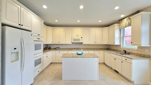 kitchen featuring white appliances, a center island, and white cabinetry