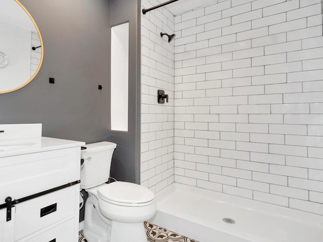 bathroom with tiled shower, vanity, and toilet