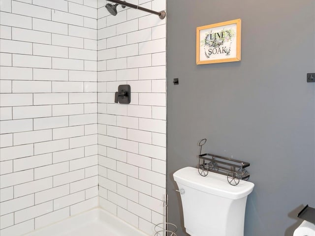 bathroom featuring tiled shower and toilet