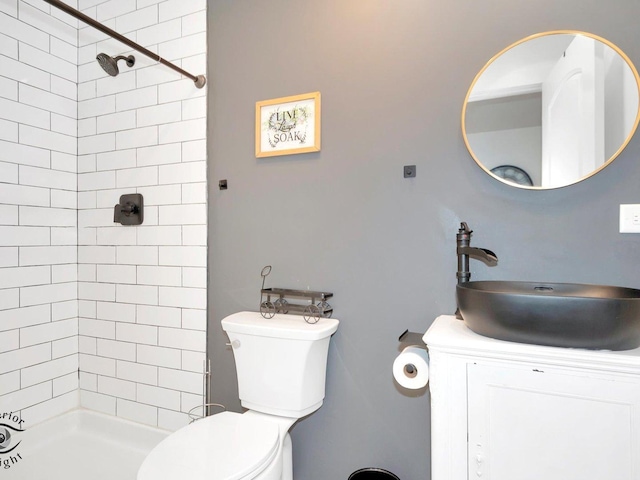 bathroom with a tile shower, vanity, and toilet