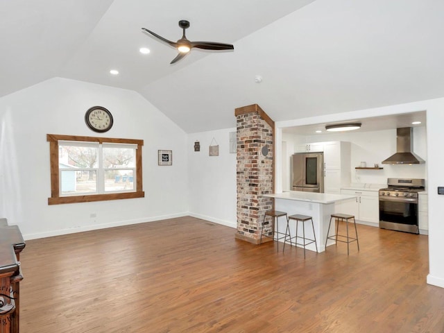 unfurnished living room with ceiling fan, wood-type flooring, and vaulted ceiling