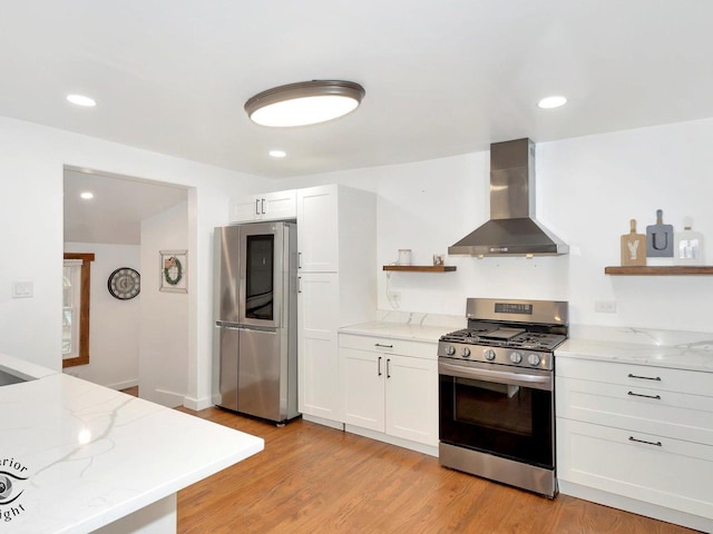 kitchen featuring white cabinetry, light hardwood / wood-style flooring, wall chimney range hood, and appliances with stainless steel finishes