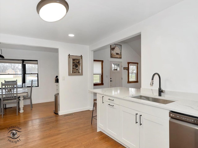 kitchen featuring light stone counters, stainless steel dishwasher, sink, light hardwood / wood-style flooring, and white cabinets