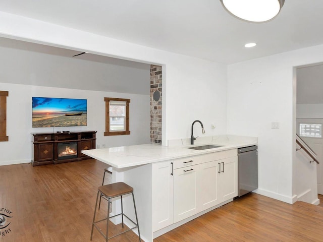 kitchen featuring white cabinets, light wood-type flooring, a breakfast bar, and kitchen peninsula