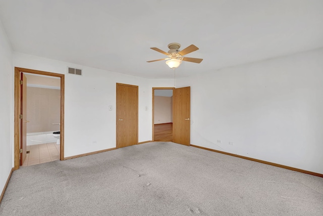 unfurnished bedroom featuring light carpet, ensuite bathroom, and ceiling fan