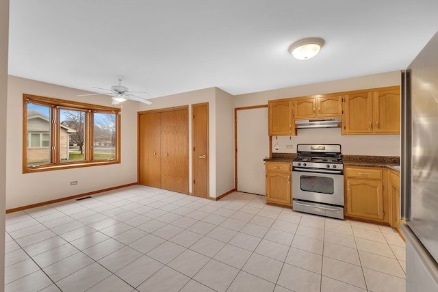 kitchen featuring ceiling fan, light tile patterned flooring, dark stone countertops, and stainless steel appliances