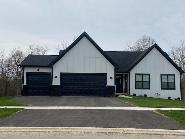 modern inspired farmhouse with a front yard and a garage