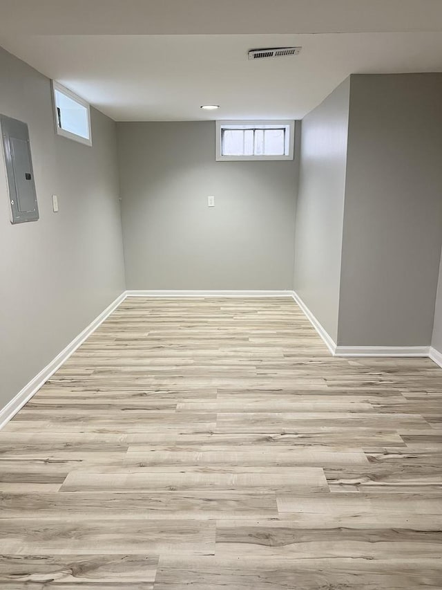 basement with light wood-type flooring and electric panel