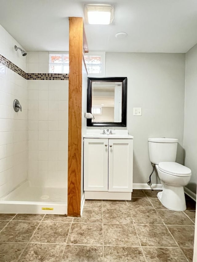 bathroom with a tile shower, vanity, and toilet