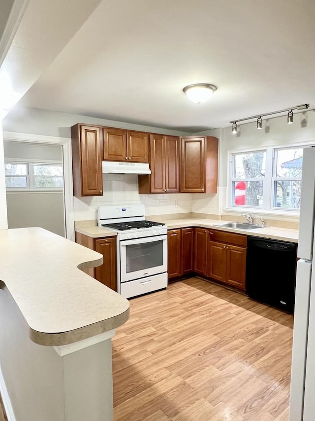 kitchen featuring light wood-type flooring, decorative backsplash, white appliances, and plenty of natural light