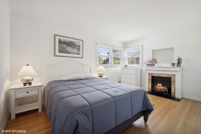 bedroom with a fireplace and light wood-type flooring