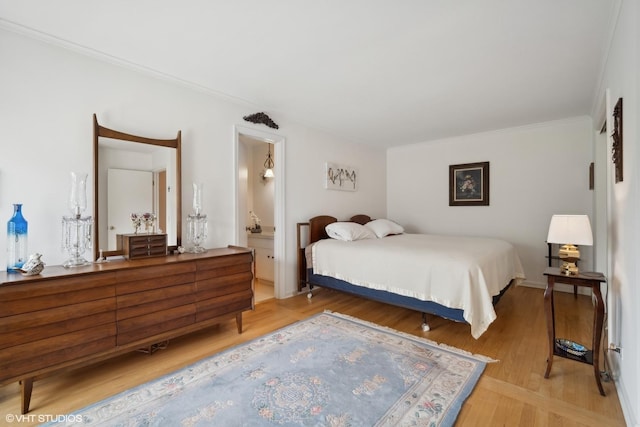 bedroom with hardwood / wood-style floors, ensuite bathroom, and crown molding