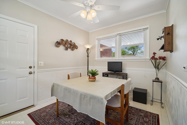 tiled dining room with ceiling fan and crown molding