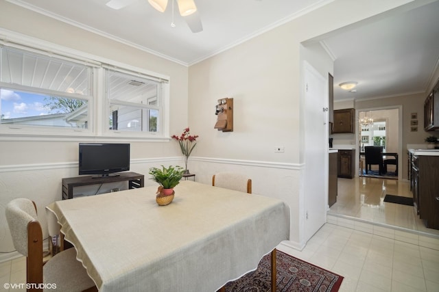 dining space with light tile patterned floors, ceiling fan with notable chandelier, and ornamental molding