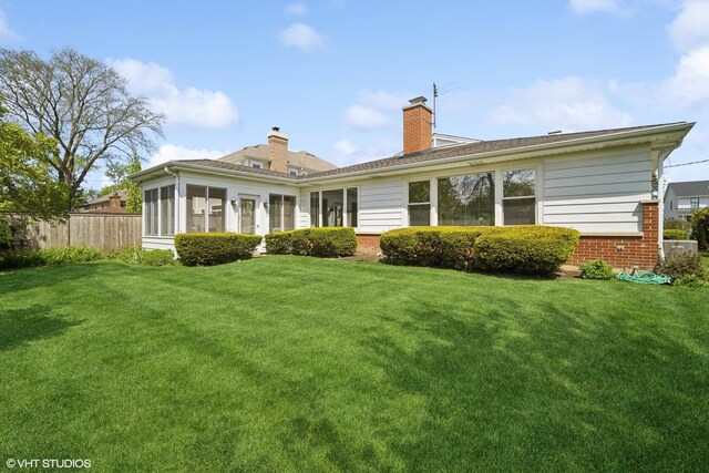 back of house with a lawn and a sunroom