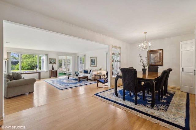 dining space with light wood-type flooring and a notable chandelier