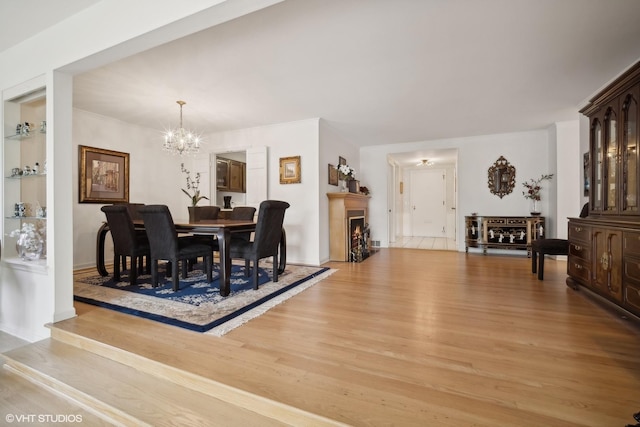 dining area with light hardwood / wood-style flooring and an inviting chandelier