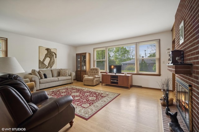 living room featuring light wood-type flooring and a brick fireplace