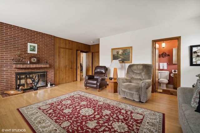 living room with hardwood / wood-style flooring, wood walls, and a brick fireplace