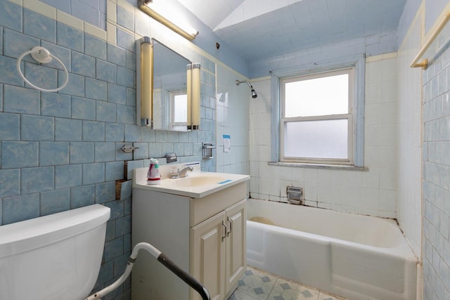 full bathroom with vanity, tiled shower / bath combo, tile walls, tile patterned flooring, and toilet