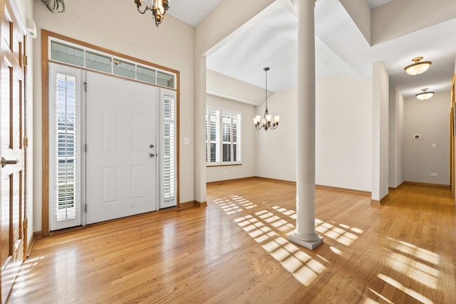 entrance foyer featuring decorative columns, light hardwood / wood-style floors, a wealth of natural light, and a chandelier