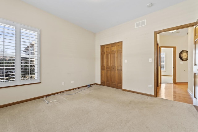 unfurnished bedroom with light carpet and a closet