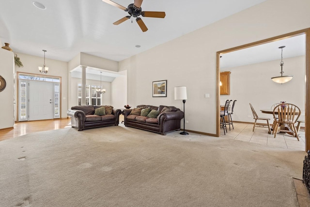 carpeted living room featuring ornate columns and ceiling fan with notable chandelier