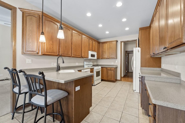 kitchen featuring a breakfast bar, kitchen peninsula, sink, white appliances, and hanging light fixtures