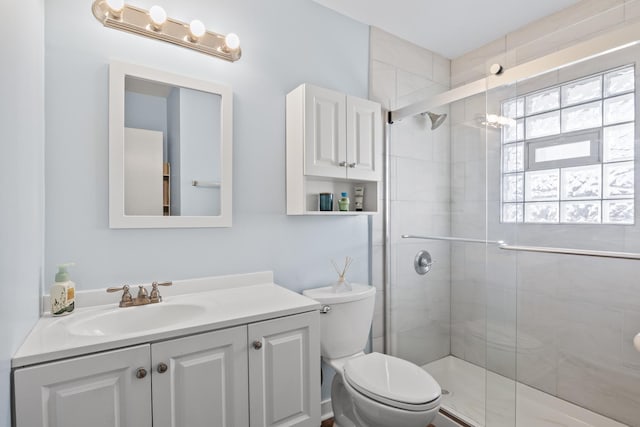 bathroom featuring vanity, a shower with shower door, and toilet