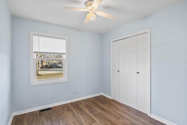 unfurnished bedroom featuring dark wood-type flooring, ceiling fan, and a closet