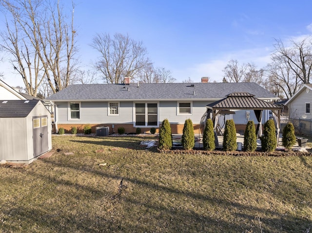 rear view of property featuring cooling unit, a storage shed, a gazebo, and a lawn