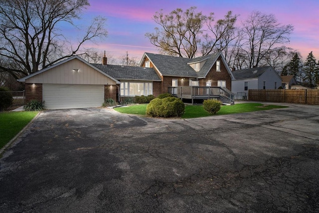 view of front of home featuring driveway, brick siding, a front lawn, and fence