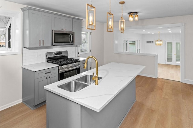 kitchen with pendant lighting, gray cabinets, sink, and stainless steel appliances