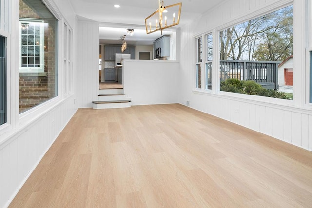 interior space featuring light wood finished floors and an inviting chandelier