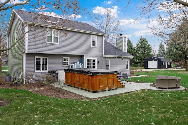 back of property featuring a chimney, a hot tub, a patio, central AC, and a yard