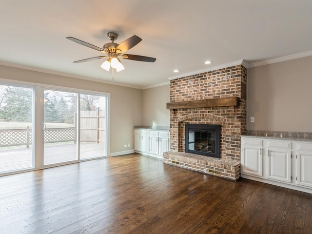 unfurnished living room with wood-type flooring, a brick fireplace, ceiling fan, and ornamental molding