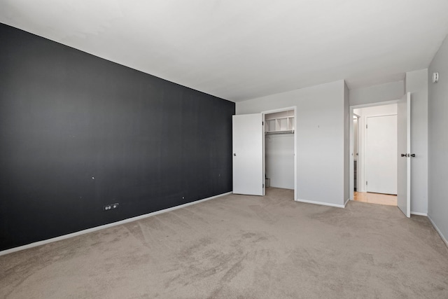 unfurnished bedroom with a closet and light colored carpet