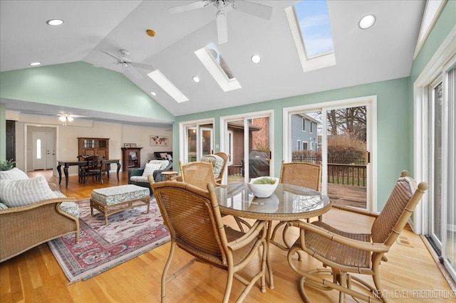 dining area with lofted ceiling with skylight, ceiling fan, and light wood-type flooring