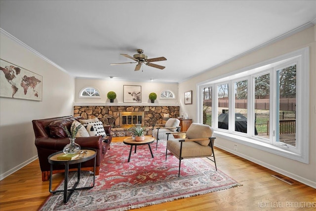 living room with ornamental molding, a fireplace, and light hardwood / wood-style floors