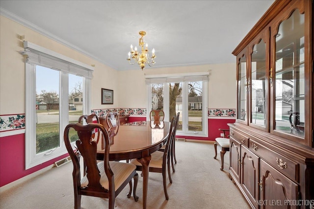 carpeted dining space featuring ornamental molding, a wealth of natural light, and a notable chandelier