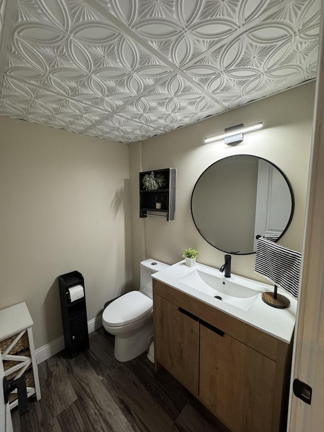 half bath featuring toilet, an ornate ceiling, baseboards, and wood finished floors