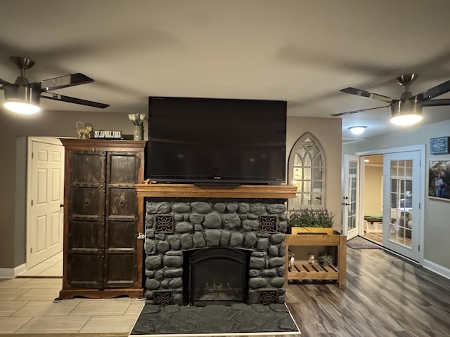 living area featuring a fireplace, wood finished floors, a ceiling fan, and baseboards