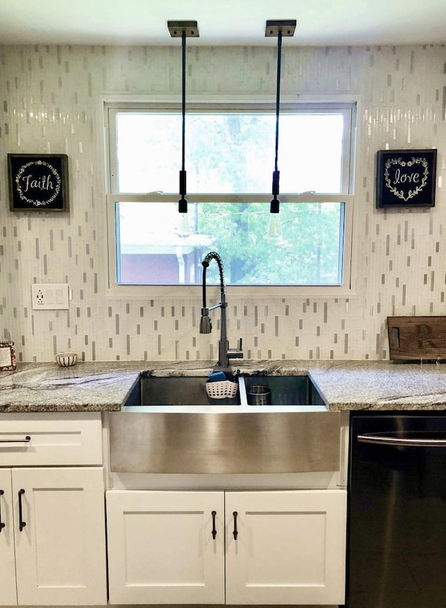 kitchen featuring dishwashing machine, a sink, white cabinets, and wallpapered walls