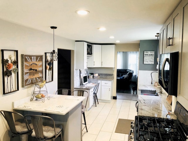 kitchen with recessed lighting, white cabinetry, a sink, light stone countertops, and a kitchen breakfast bar