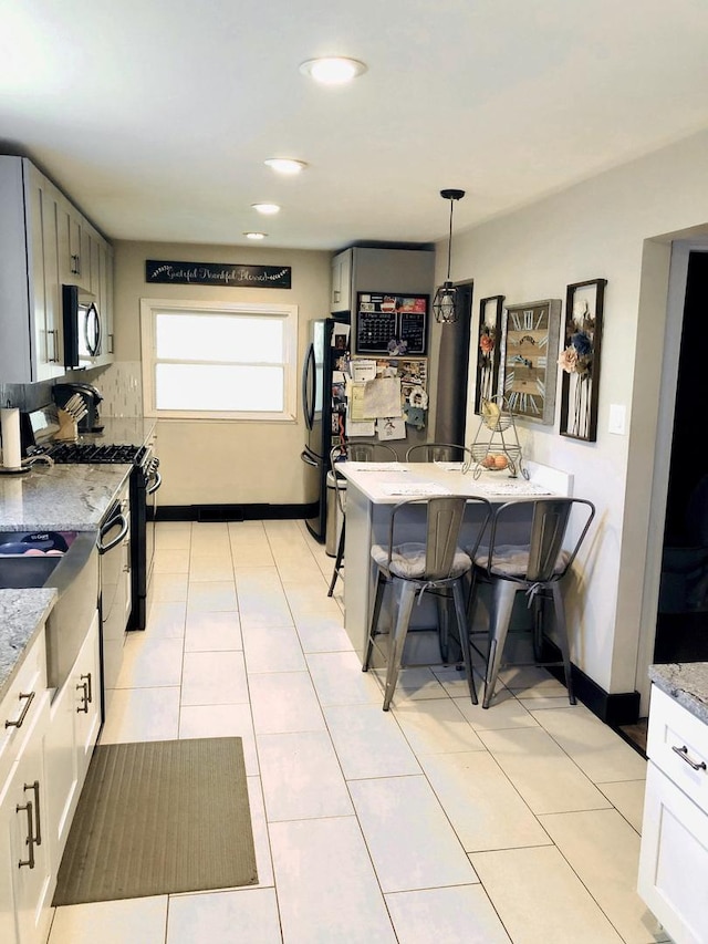 kitchen with light stone counters, pendant lighting, black appliances, and light tile patterned floors