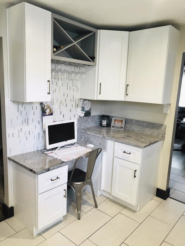 kitchen featuring light tile patterned floors, backsplash, white cabinetry, and light stone countertops