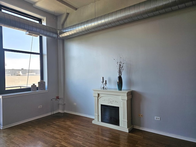 unfurnished living room featuring plenty of natural light and dark wood-type flooring