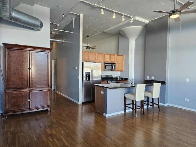 kitchen with stainless steel appliances, dark hardwood / wood-style floors, kitchen peninsula, a towering ceiling, and a breakfast bar area